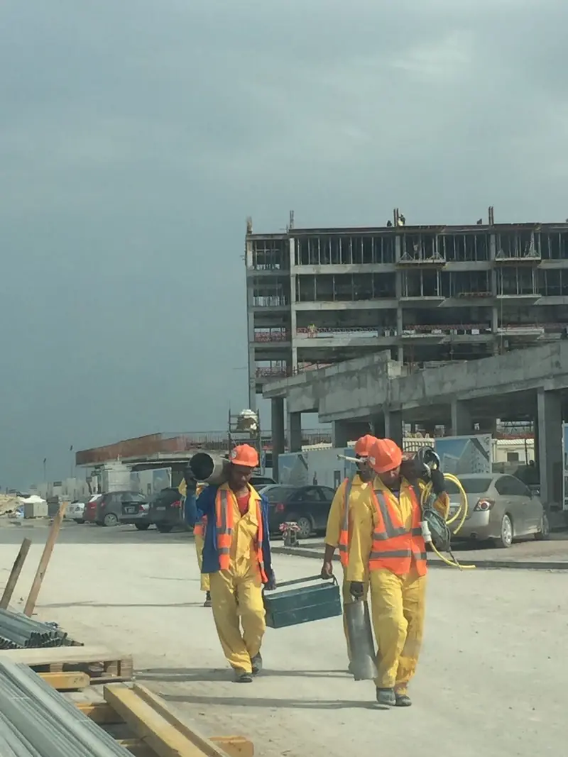 Aseel Constructions crew carrying equipment on a building site in Qatar